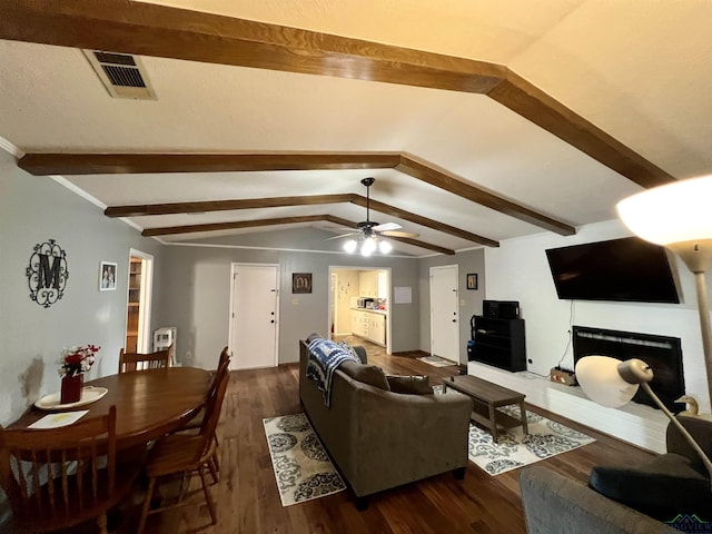 1523 Young St, Henderson, TX 75654 - living area with visible vents, a brick fireplace, vaulted ceiling with beams, wood finished floors, and a ceiling fan