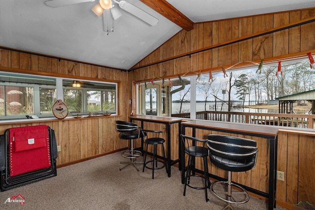 bar with lofted ceiling with beams, light carpet, ceiling fan, and wood walls