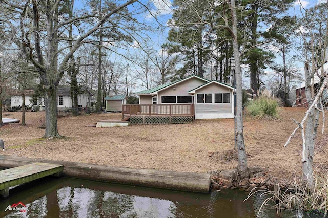 rear view of house featuring a sunroom and a deck with water view