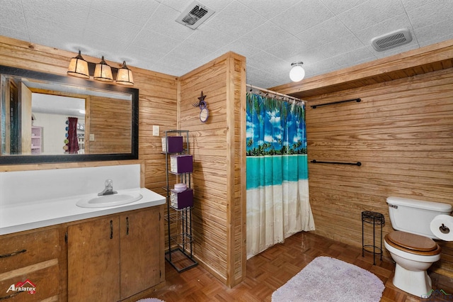 bathroom with wooden walls, vanity, parquet flooring, toilet, and walk in shower