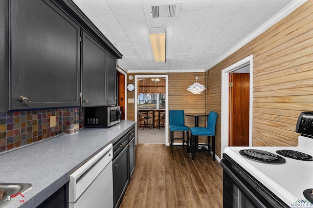 kitchen with dark wood-type flooring, electric range oven, hanging light fixtures, white dishwasher, and ornamental molding