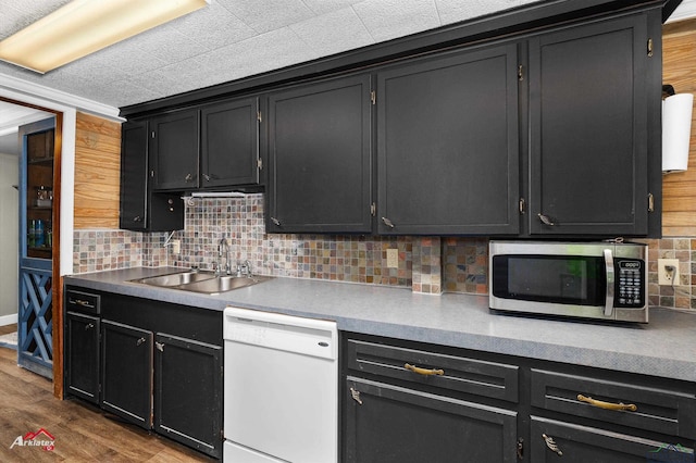 kitchen featuring tasteful backsplash, wood-type flooring, white dishwasher, and sink