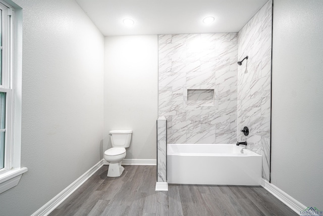 bathroom featuring hardwood / wood-style flooring, toilet, and tiled shower / bath