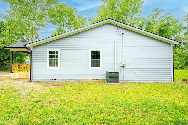 view of side of property with central AC unit and a yard