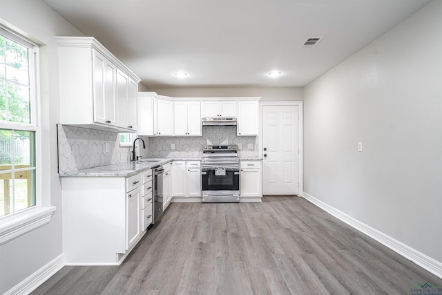 kitchen with backsplash, sink, light stone counters, white cabinetry, and stainless steel appliances