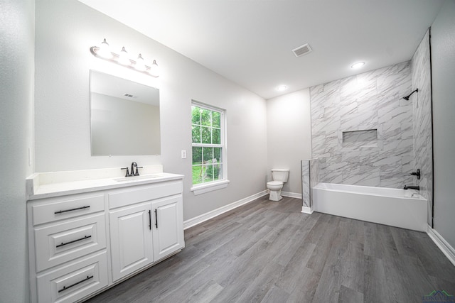 full bathroom with toilet, vanity, wood-type flooring, and tiled shower / bath