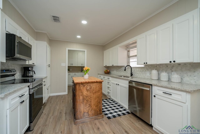 3697 N White Oak Rd, Gladewater, TX 75647 - kitchen featuring appliances with stainless steel finishes, crown molding, backsplash, white cabinets, and a sink
