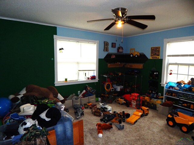 playroom featuring carpet flooring, a wealth of natural light, ceiling fan, and ornamental molding