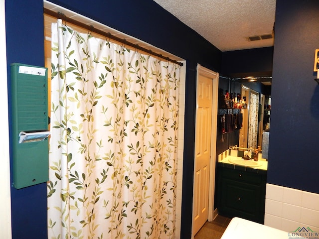 bathroom featuring vanity, a shower, and a textured ceiling