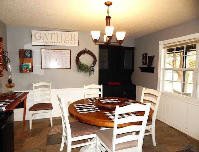 dining space with a textured ceiling and an inviting chandelier