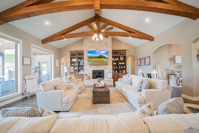 living room featuring hardwood / wood-style flooring, a stone fireplace, ceiling fan, and beam ceiling