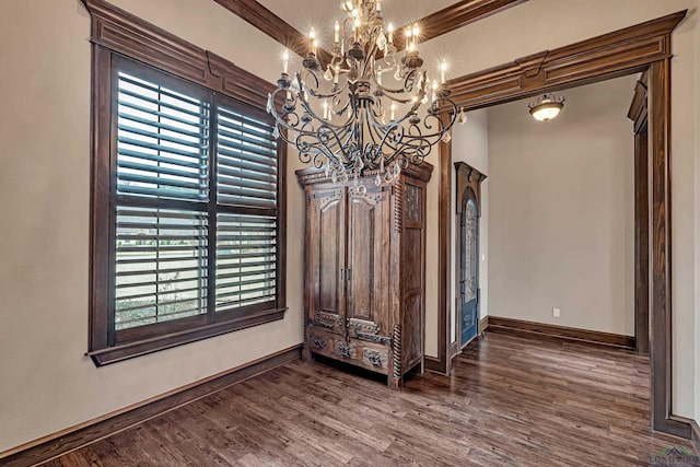 spare room with dark wood finished floors, baseboards, and an inviting chandelier