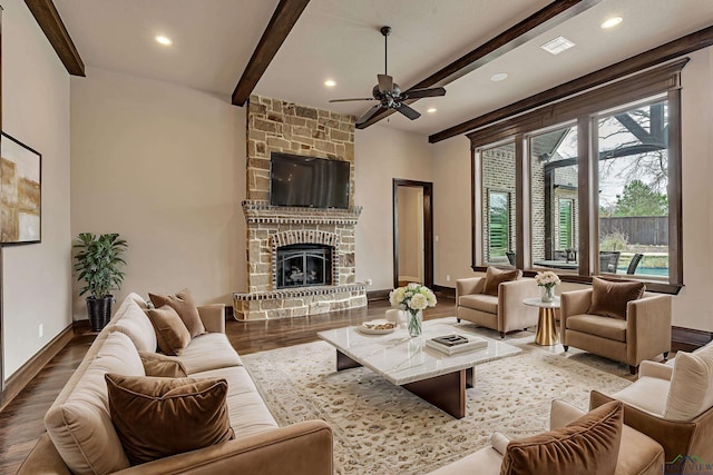 living room featuring a stone fireplace, recessed lighting, wood finished floors, baseboards, and beamed ceiling