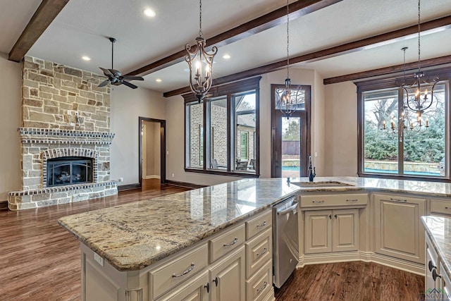 kitchen with a fireplace, a sink, open floor plan, light stone countertops, and dishwasher