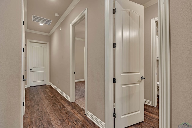 corridor with ornamental molding, dark wood-type flooring, visible vents, and baseboards