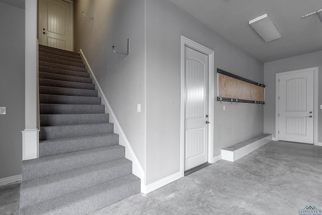 stairway featuring concrete floors and baseboards