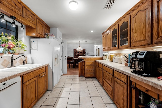 kitchen with light tile patterned floors, white appliances, hanging light fixtures, and sink