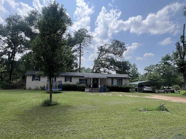 ranch-style house featuring a front yard, a carport, and a trampoline