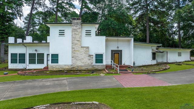 1228 Hillcrest Dr, Longview, TX 75601 - view of front facade with stucco siding, stone siding, a front lawn, and a chimney