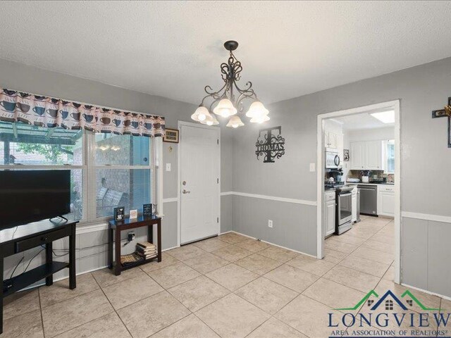 1009 Sequoyah Ln, Longview, TX 75605 - dining room with light tile patterned flooring, a chandelier, and a textured ceiling