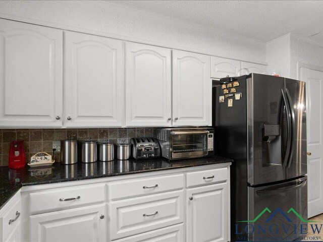 1009 Sequoyah Ln, Longview, TX 75605 - kitchen with stainless steel fridge, crown molding, white cabinetry, decorative backsplash, and dark stone counters