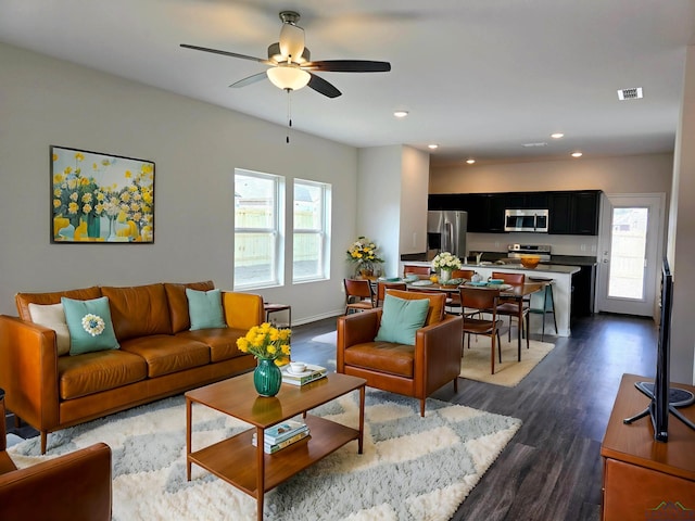 living room featuring ceiling fan and dark hardwood / wood-style floors