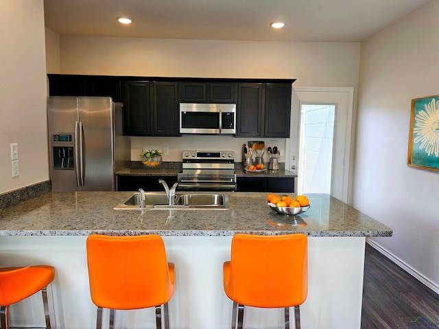 kitchen with sink, a breakfast bar, stainless steel appliances, dark hardwood / wood-style flooring, and kitchen peninsula