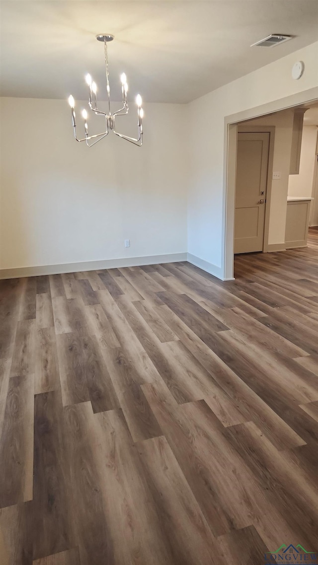 unfurnished dining area with a notable chandelier, visible vents, and dark wood-style flooring