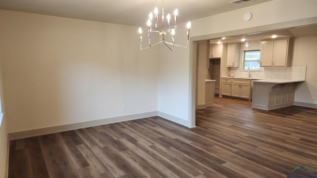 unfurnished dining area featuring dark wood-type flooring, an inviting chandelier, visible vents, and baseboards