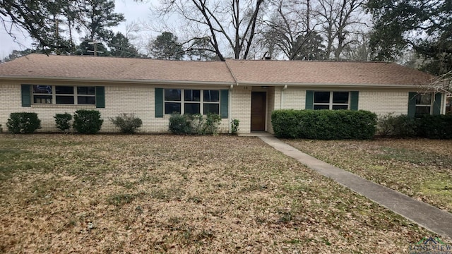 ranch-style house with brick siding, a front yard, and a shingled roof