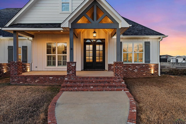 exterior entry at dusk featuring french doors and covered porch