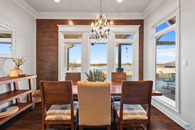 dining area featuring an inviting chandelier, a water view, dark hardwood / wood-style floors, and crown molding