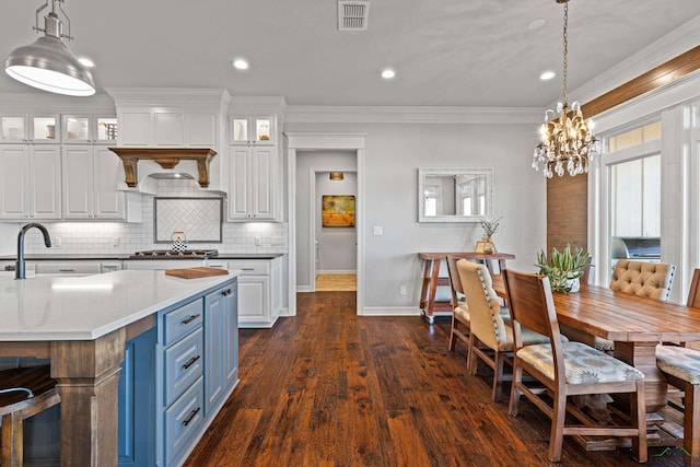 kitchen with blue cabinets, sink, white cabinetry, crown molding, and pendant lighting