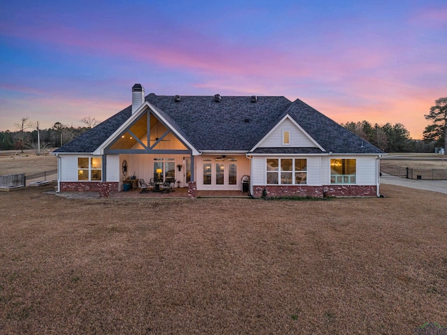 back house at dusk with ceiling fan, a yard, and a patio area