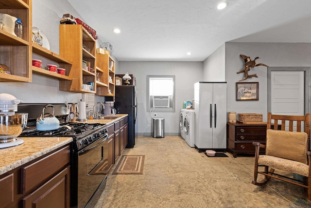 kitchen with sink, cooling unit, washer and clothes dryer, and black appliances