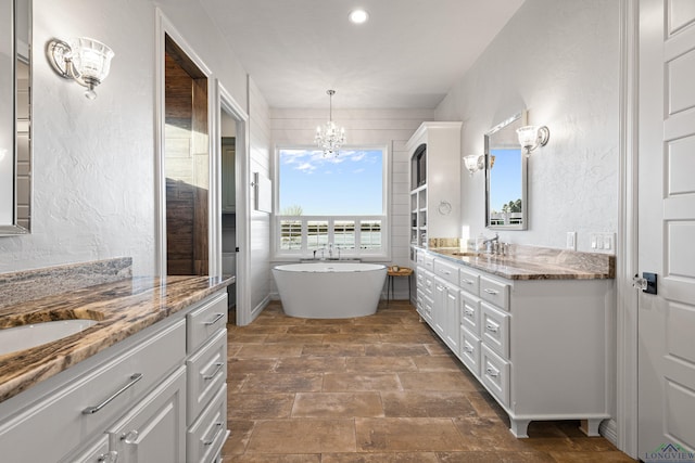 bathroom featuring vanity, a bathtub, and an inviting chandelier