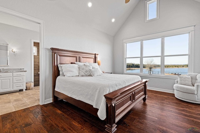 bedroom with a water view, wood-type flooring, and high vaulted ceiling