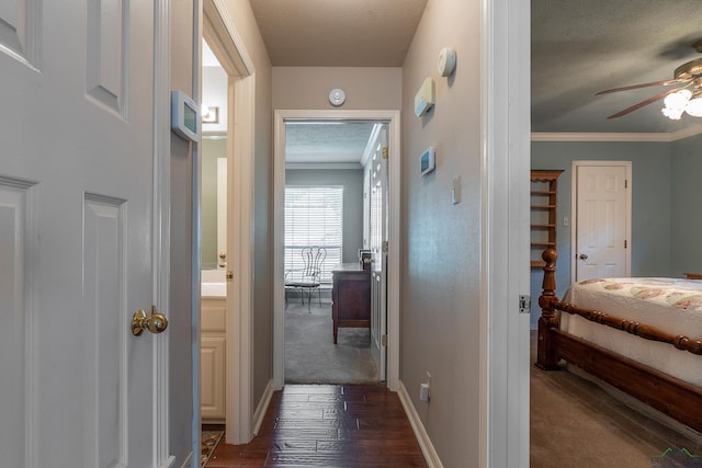 hall with a textured ceiling, dark hardwood / wood-style floors, and ornamental molding