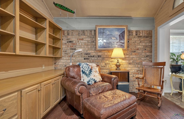 living area featuring lofted ceiling, brick wall, and dark hardwood / wood-style floors