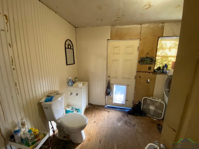 bathroom with washer / clothes dryer, a wealth of natural light, hardwood / wood-style floors, and toilet