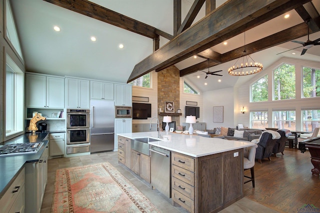 kitchen featuring high vaulted ceiling, sink, built in appliances, a large island, and beam ceiling