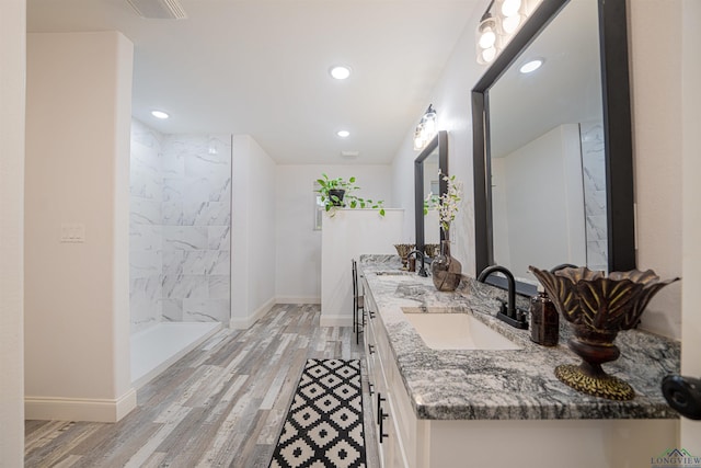 bathroom featuring hardwood / wood-style floors, vanity, and tiled shower