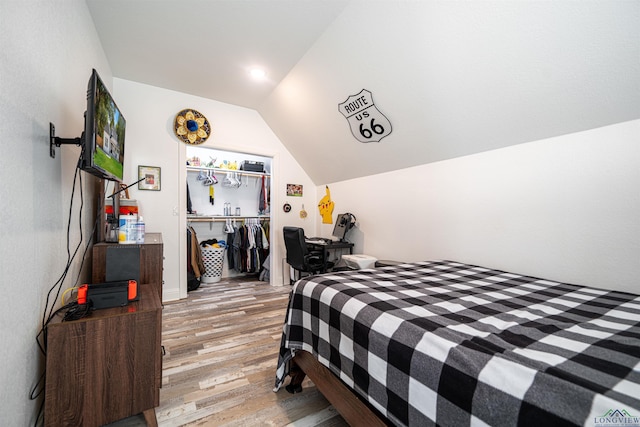 bedroom with light hardwood / wood-style floors, lofted ceiling, and a closet