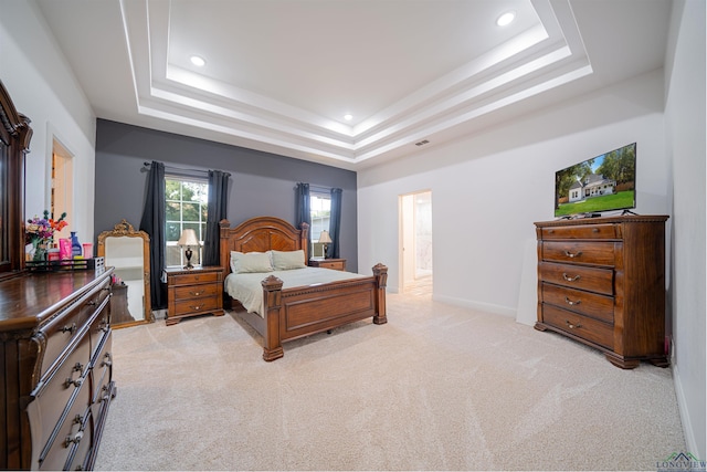 bedroom featuring a raised ceiling and light carpet