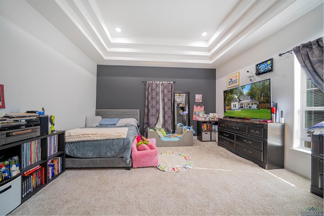 bedroom with light colored carpet and a tray ceiling