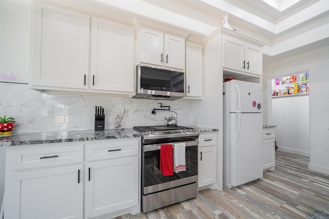 kitchen featuring stone counters, tasteful backsplash, appliances with stainless steel finishes, white cabinets, and light wood-type flooring