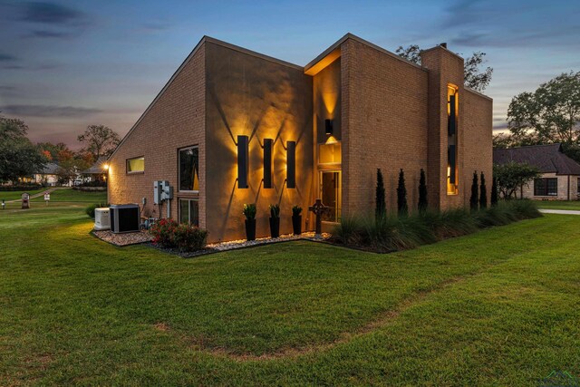 property exterior at dusk featuring a lawn and central air condition unit