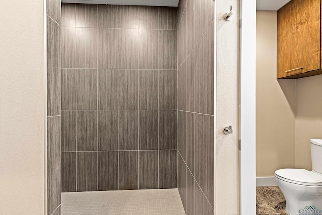 bathroom with a tile shower and toilet