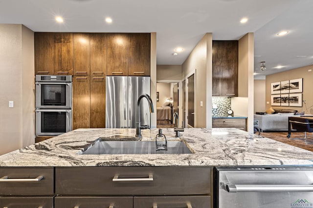 kitchen featuring light stone counters, sink, stainless steel appliances, and tasteful backsplash