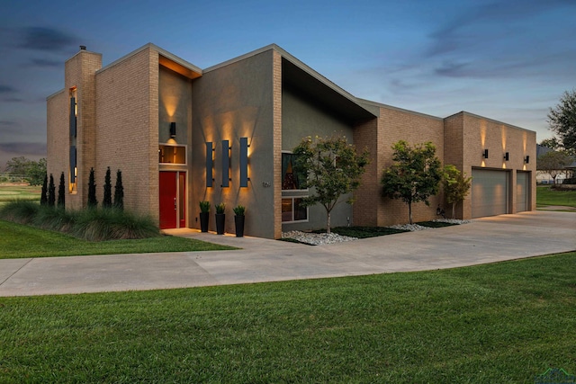 property exterior at dusk with a garage and a lawn